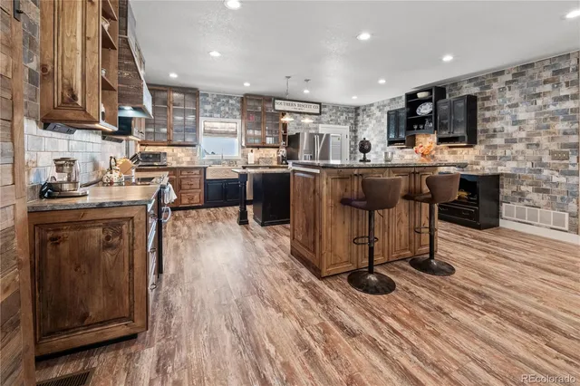 a kitchen with stainless steel appliances kitchen island granite countertop a table chairs sink and cabinets