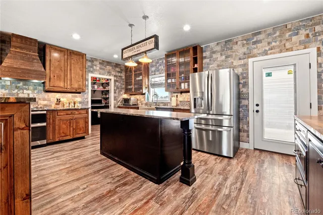 a kitchen with stainless steel appliances granite countertop a refrigerator a sink dishwasher a stove with wooden floor and cabinets