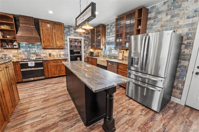 a kitchen with stainless steel appliances granite countertop a refrigerator a stove and a sink