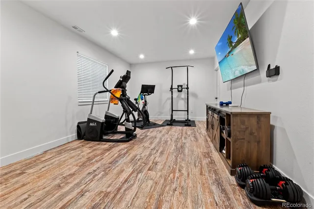 a view of a room with gym equipment and wooden floor