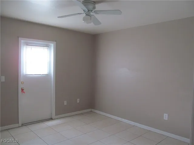 an empty room with a ceiling fan and a window