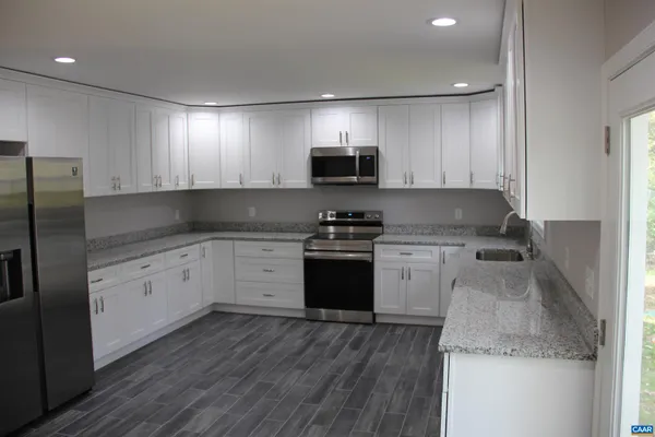 a kitchen with granite countertop white cabinets and stainless steel appliances