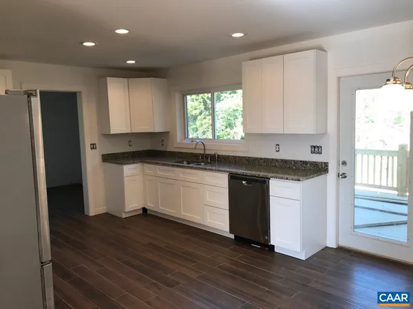 a kitchen with granite countertop white cabinets and wooden floor