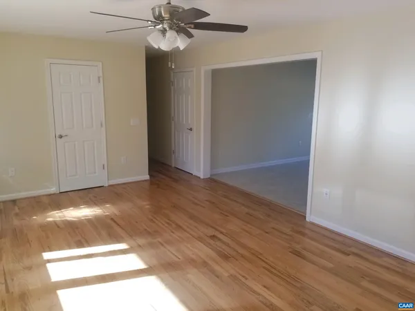 an empty room with wooden floor closet and windows