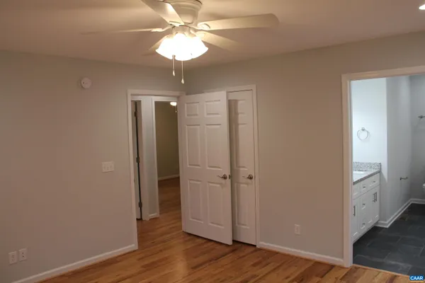 an empty room with wooden floor and a ceiling fan