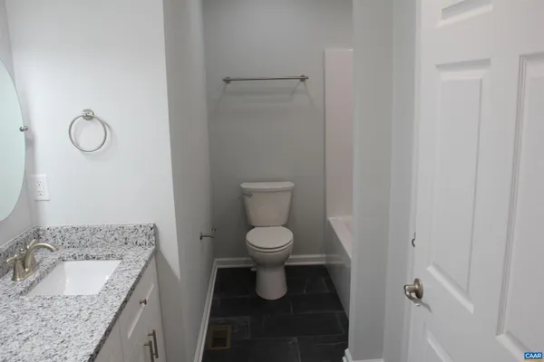 a bathroom with a granite countertop toilet and a sink