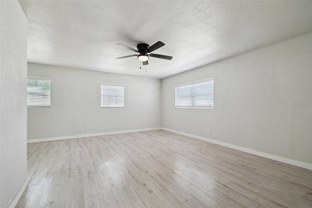 3414 Lindsey Street Dover, FL 33527 - Photo 22 of 45 an empty room with wooden floor ceiling fan and windows