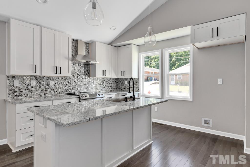 519 Barton Street Durham, NC 27707 - Photo 2 of 9 a kitchen with stainless steel appliances granite countertop a sink a stove a dining table and wooden cabinets