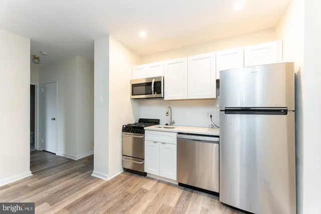 a kitchen with stainless steel appliances granite countertop a refrigerator stove a sink and dishwasher with wooden floor