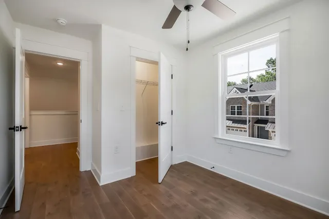 an empty room with wooden floor closet and windows