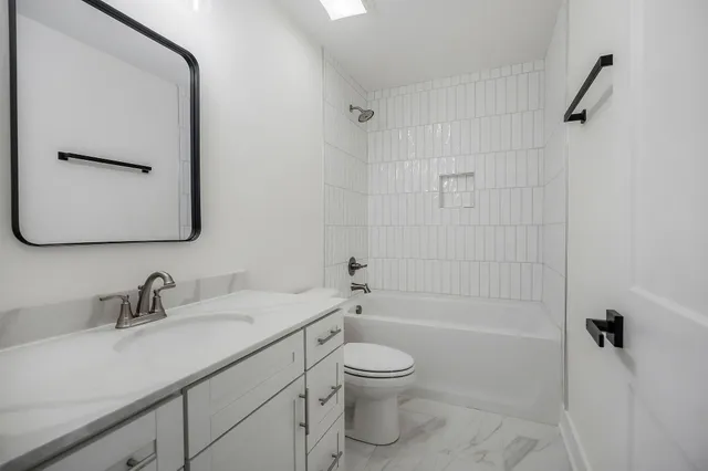a bathroom with a granite countertop sink a toilet and shower