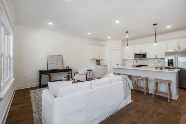 a living room with stainless steel appliances furniture a rug and a kitchen view