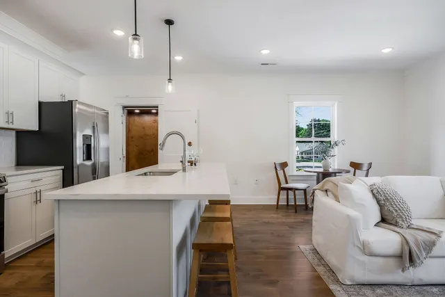 a kitchen with stainless steel appliances kitchen island granite countertop a sink a refrigerator and chairs