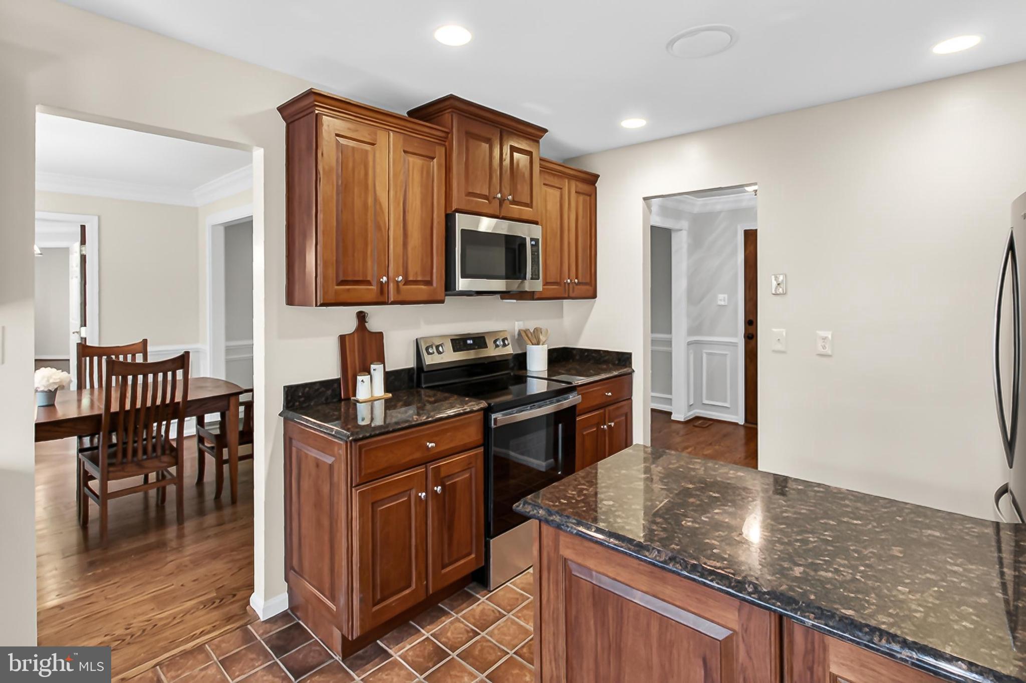 15117 Philip Lee Road Chantilly, VA 20151 - Photo 20 of 71 a kitchen with granite countertop a stove top oven a sink a dining table and chairs