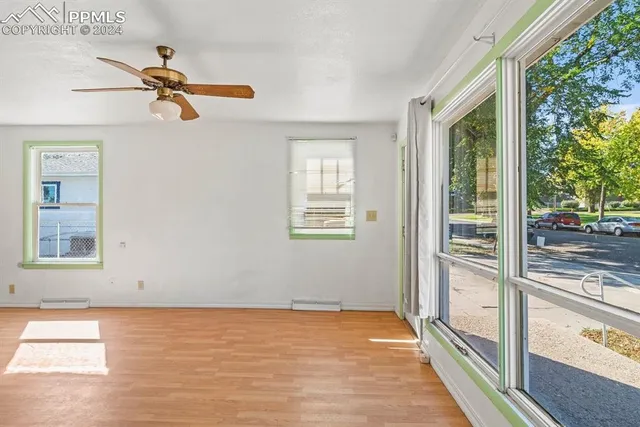 a view of empty room with wooden floor and fan
