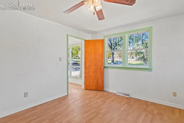 a view of an empty room with a window and wooden floor