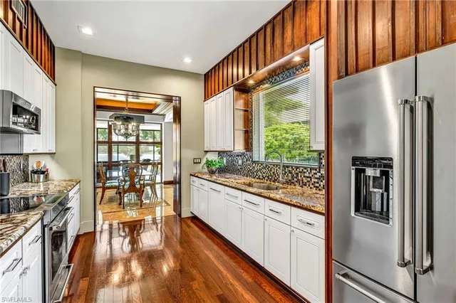 a kitchen with stainless steel appliances granite countertop a refrigerator a stove and a wooden floors