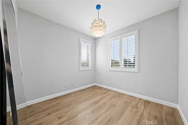 an empty room with wooden floor chandelier and windows