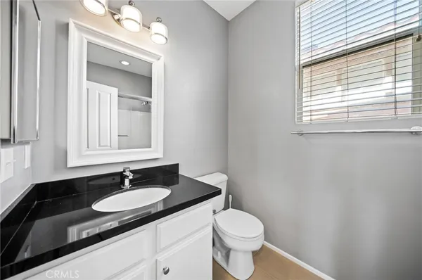 a bathroom with a granite countertop sink toilet a mirror and a window
