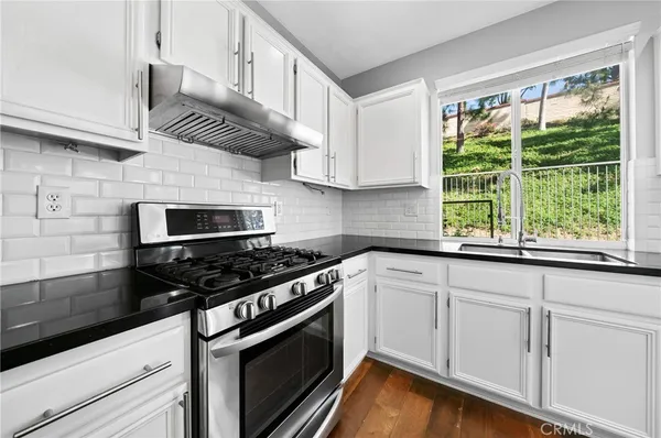 a kitchen with granite countertop stainless steel appliances a stove sink and cabinets