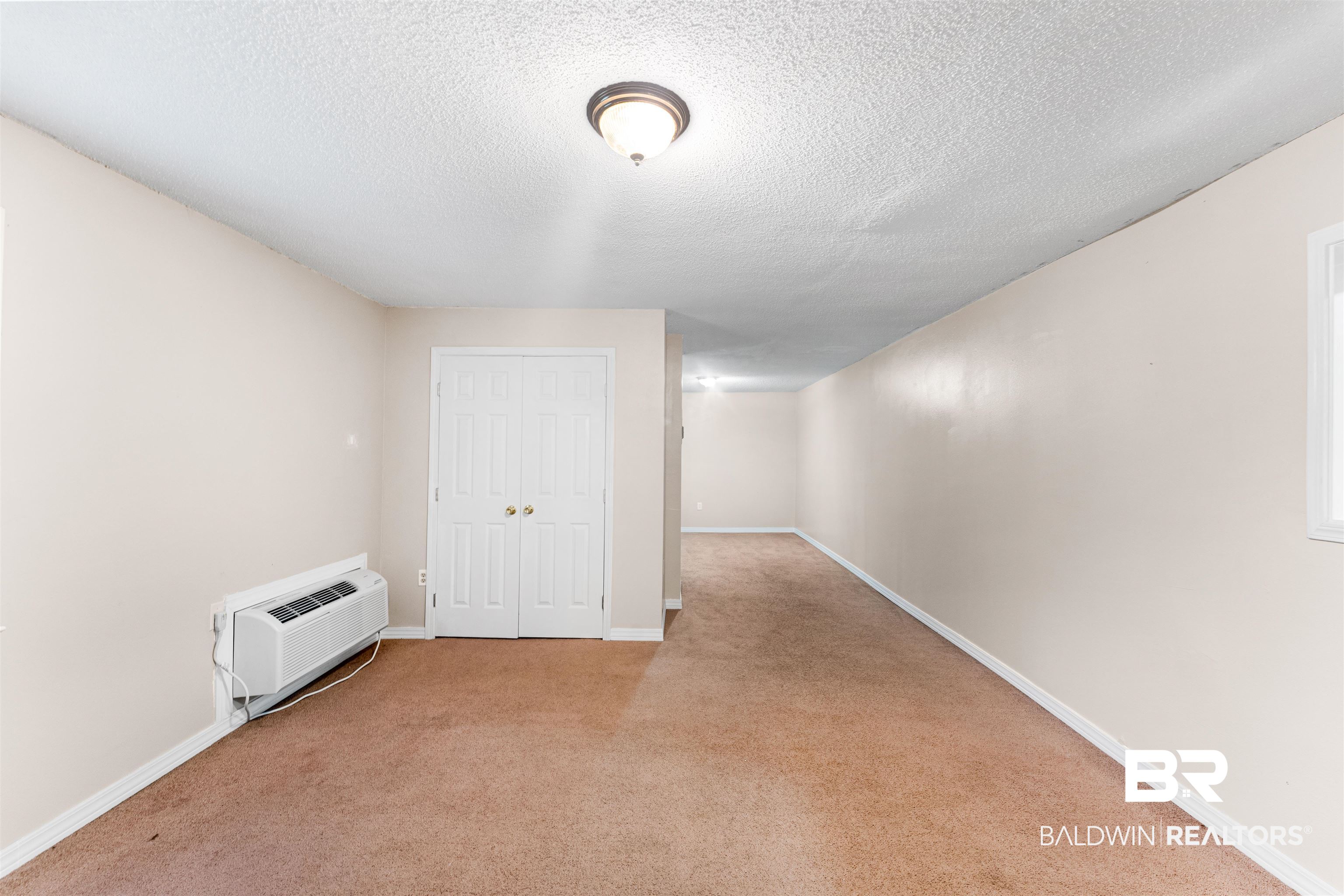 5551 Springer Court Theodore, AL 36582 - Photo 25 of 37 Empty room with an AC wall unit, carpet flooring, and a textured ceiling