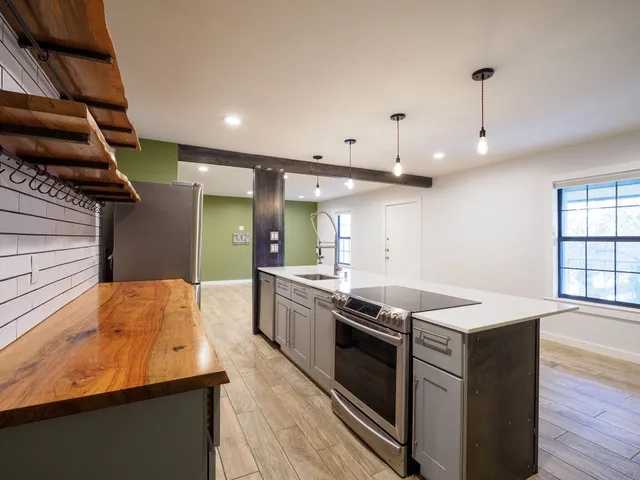 a kitchen that has a sink a stove and wooden floor