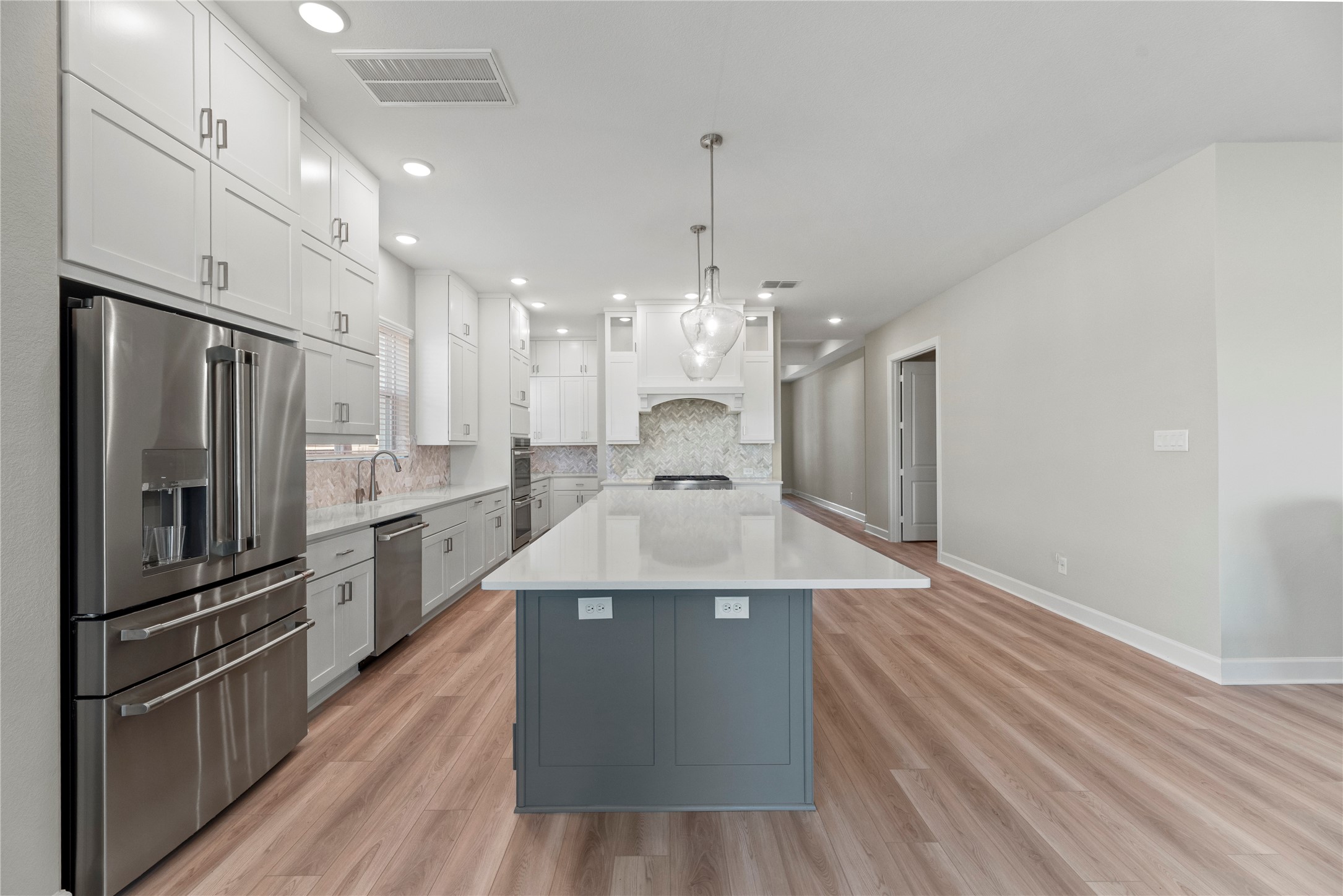 3111 Swift Way Katy, TX 77493 - Photo 24 of 50 a large kitchen with kitchen island a stove a sink dishwasher a refrigerator and white cabinets with wooden floor