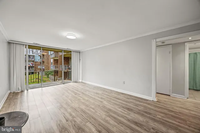 a view of empty room with wooden floor and fan