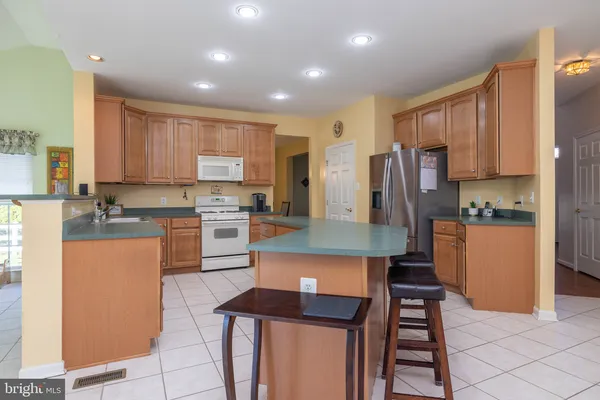 a kitchen with stainless steel appliances kitchen island granite countertop a refrigerator a stove a sink dishwasher and a oven with cabinets