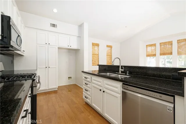 a kitchen with granite countertop a sink stainless steel appliances and cabinets