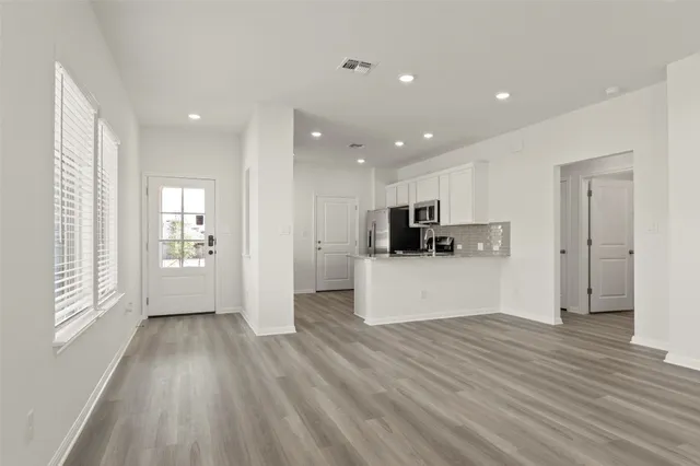 a view of kitchen with stainless steel appliances wooden floor and large window