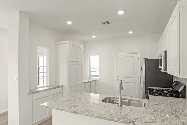 a kitchen with stainless steel appliances granite countertop a stove a sink and a microwave