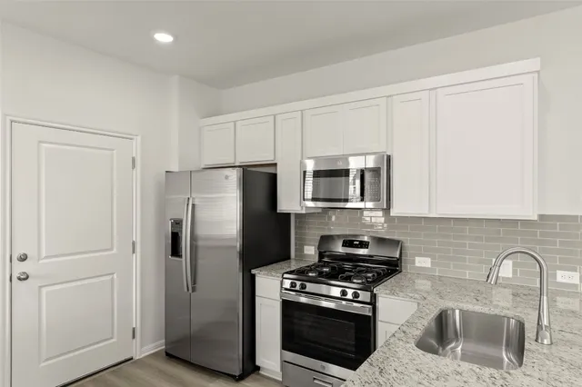 a kitchen with a refrigerator and white cabinets