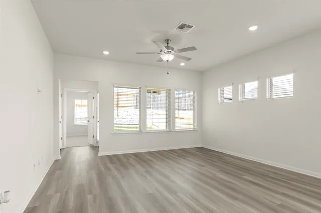 a view of an empty room with a window and wooden floor