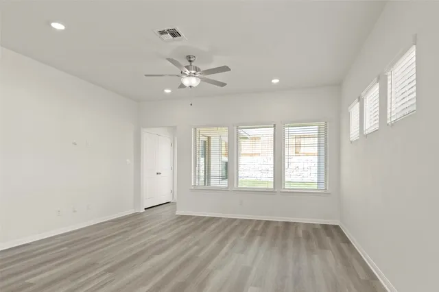an empty room with wooden floor and windows