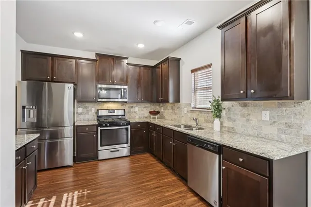 a kitchen with stainless steel appliances granite countertop a sink stove and refrigerator