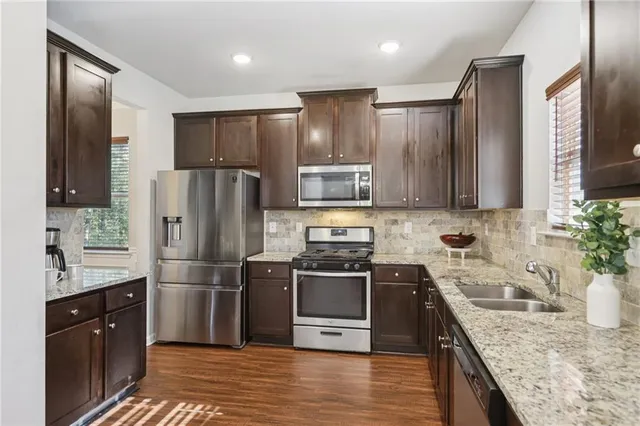 a kitchen with stainless steel appliances granite countertop a refrigerator a sink a stove and cabinets
