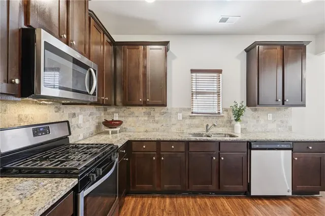 a kitchen with granite countertop a sink a stove and cabinets