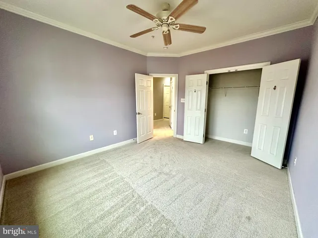 an empty room with closet and a ceiling fan