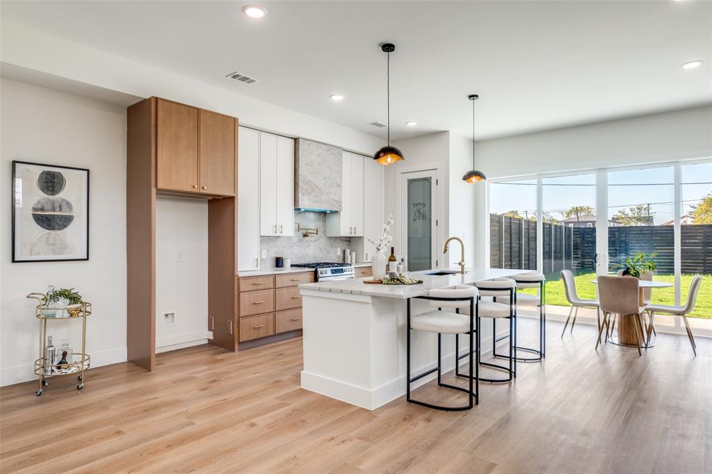 2424 Jeffries Street Dallas, TX 75215 - Photo 2 of 28 Kitchen with a breakfast bar, pendant lighting, tasteful backsplash, white cabinetry, and light wood-type flooring