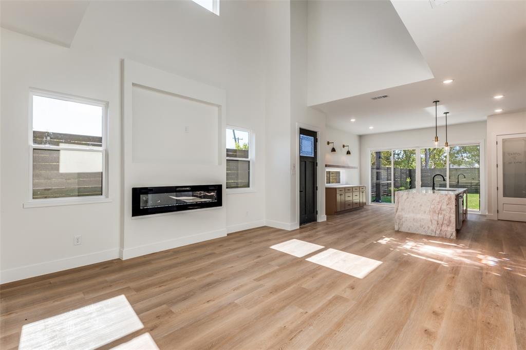 2424 Jeffries Street Dallas, TX 75215 - Photo 6 of 28 Unfurnished living room featuring a towering ceiling, a glass covered fireplace, light wood-style floors, and recessed lighting