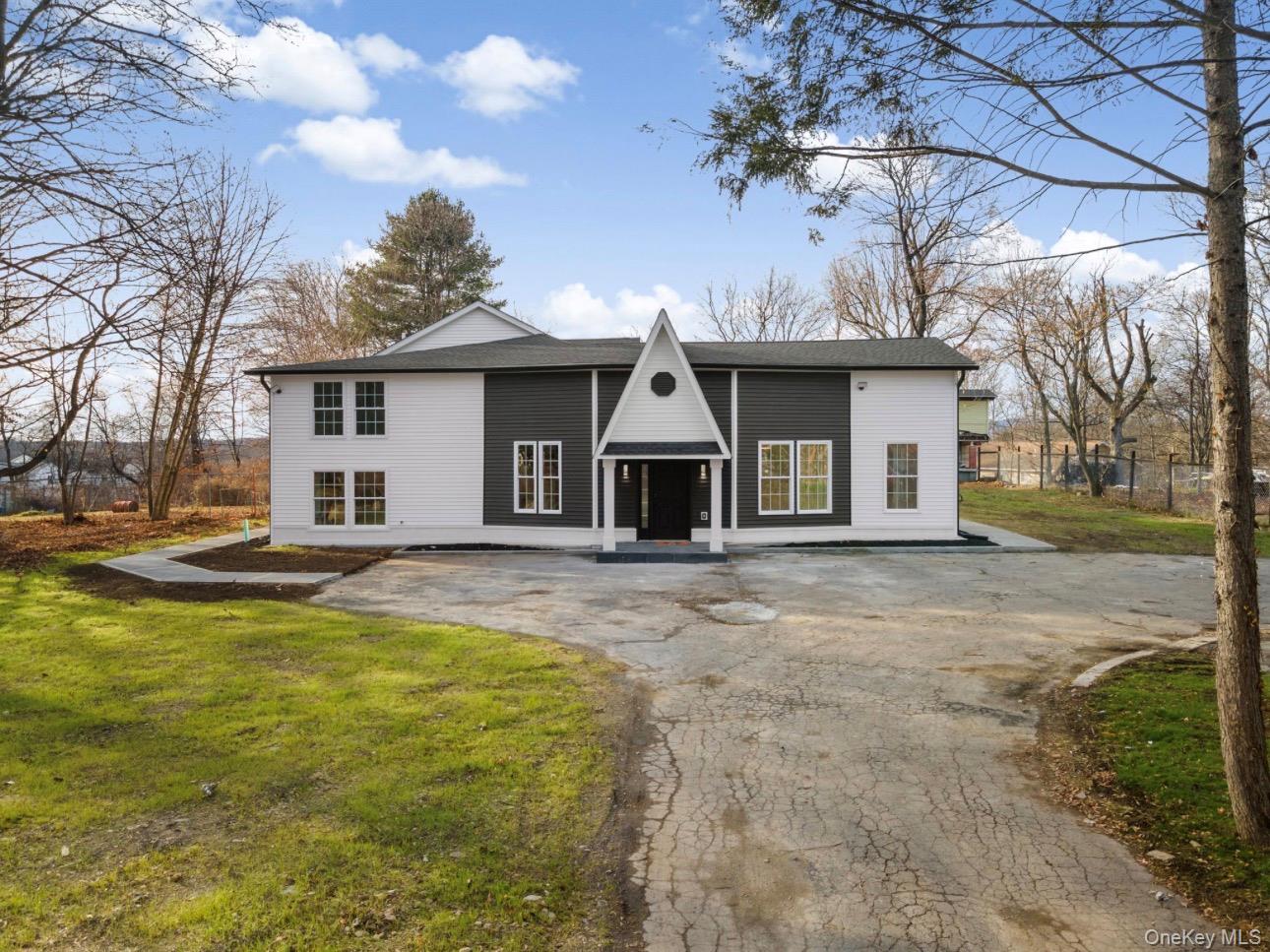 View of front facade featuring asphalt driveway and a shingled roof