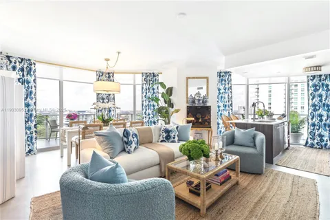 a living room with furniture a chandelier and a floor to ceiling window