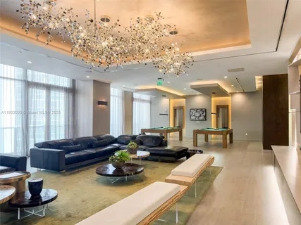 a living room with furniture a chandelier and a large window