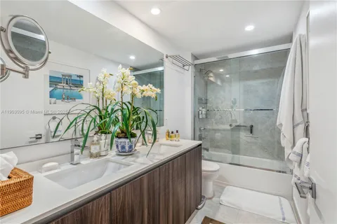 a bathroom with a granite countertop sink a toilet a mirror and shower