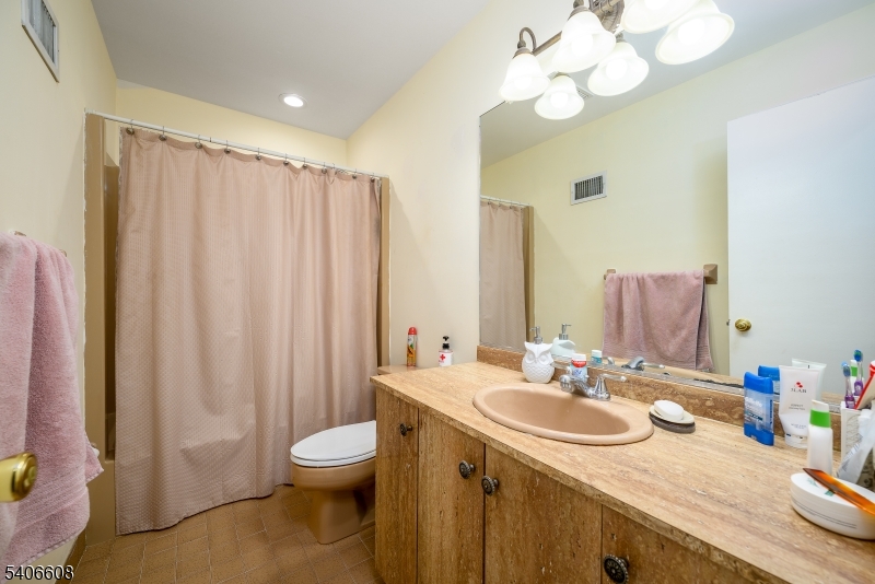 900 Valley Road, Unit D1O Clifton, NJ 07013 - Photo 14 of 16 a bathroom with a granite countertop sink a toilet and a mirror