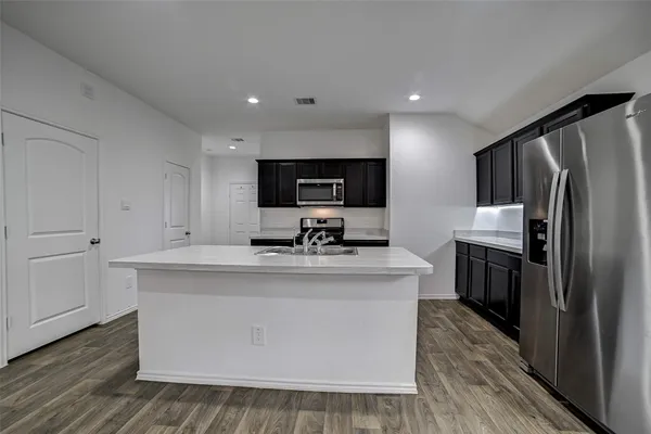 a view of kitchen with microwave stove refrigerator and cabinets