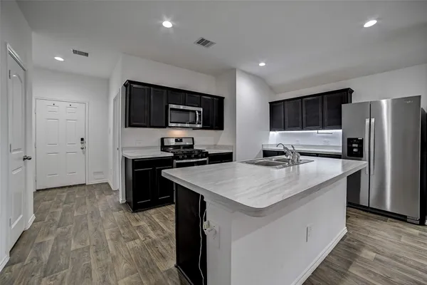 a kitchen with a sink a counter top space stainless steel appliances and cabinets