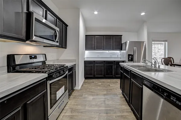 a kitchen with stainless steel appliances granite countertop a stove top oven microwave and sink