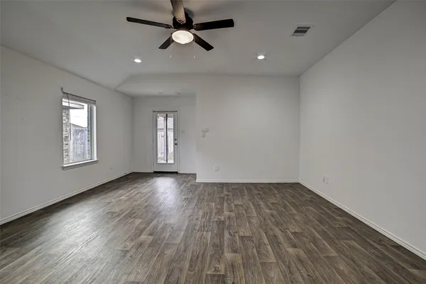 an empty room with wooden floor chandelier fan and windows